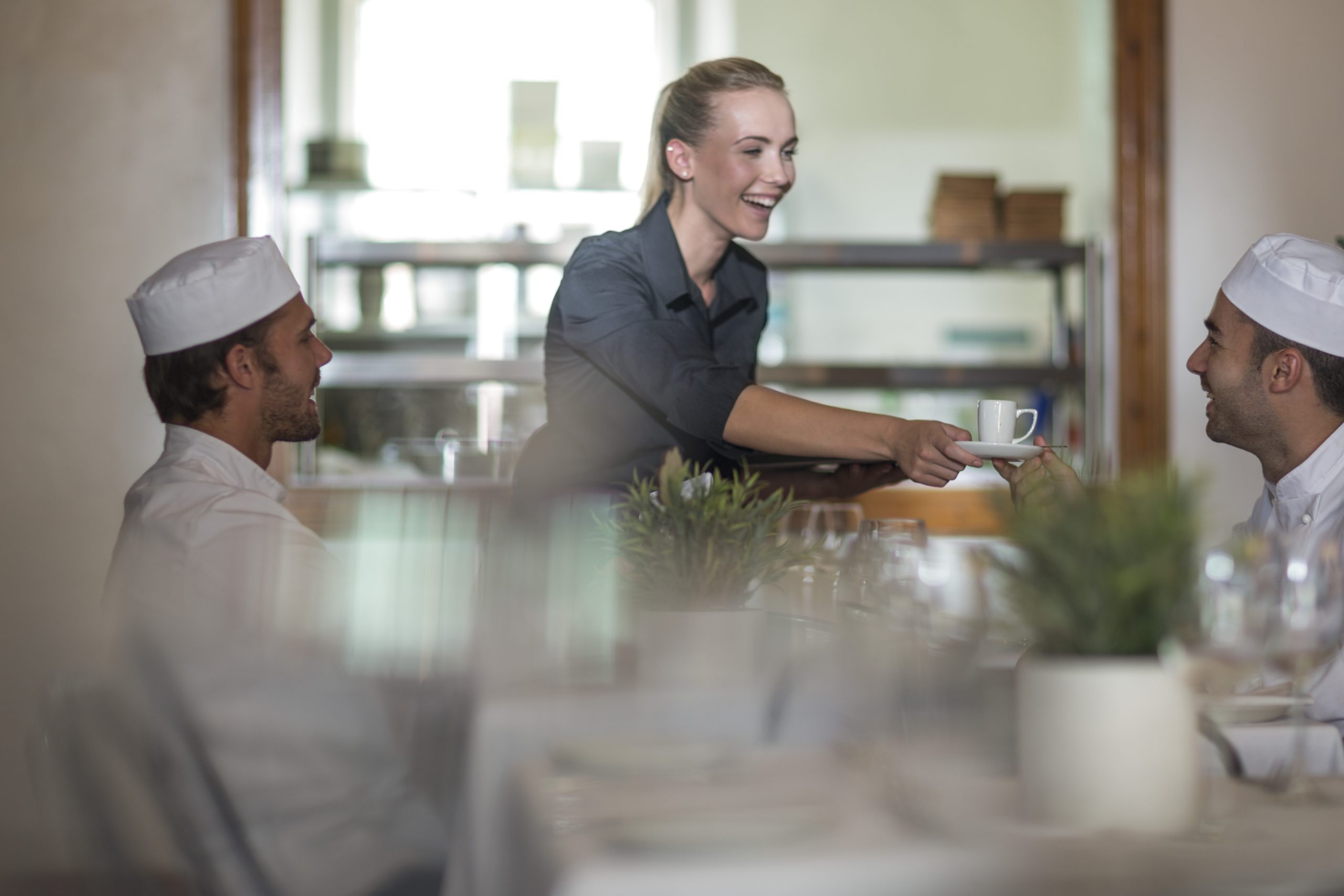 Waitress serving coffee to chefs at break time